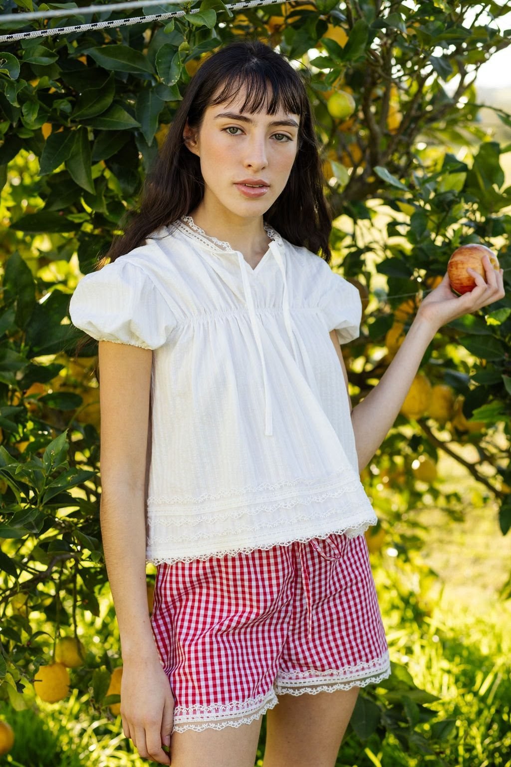 Blusa blanca y short a cuadros bajo el limonero