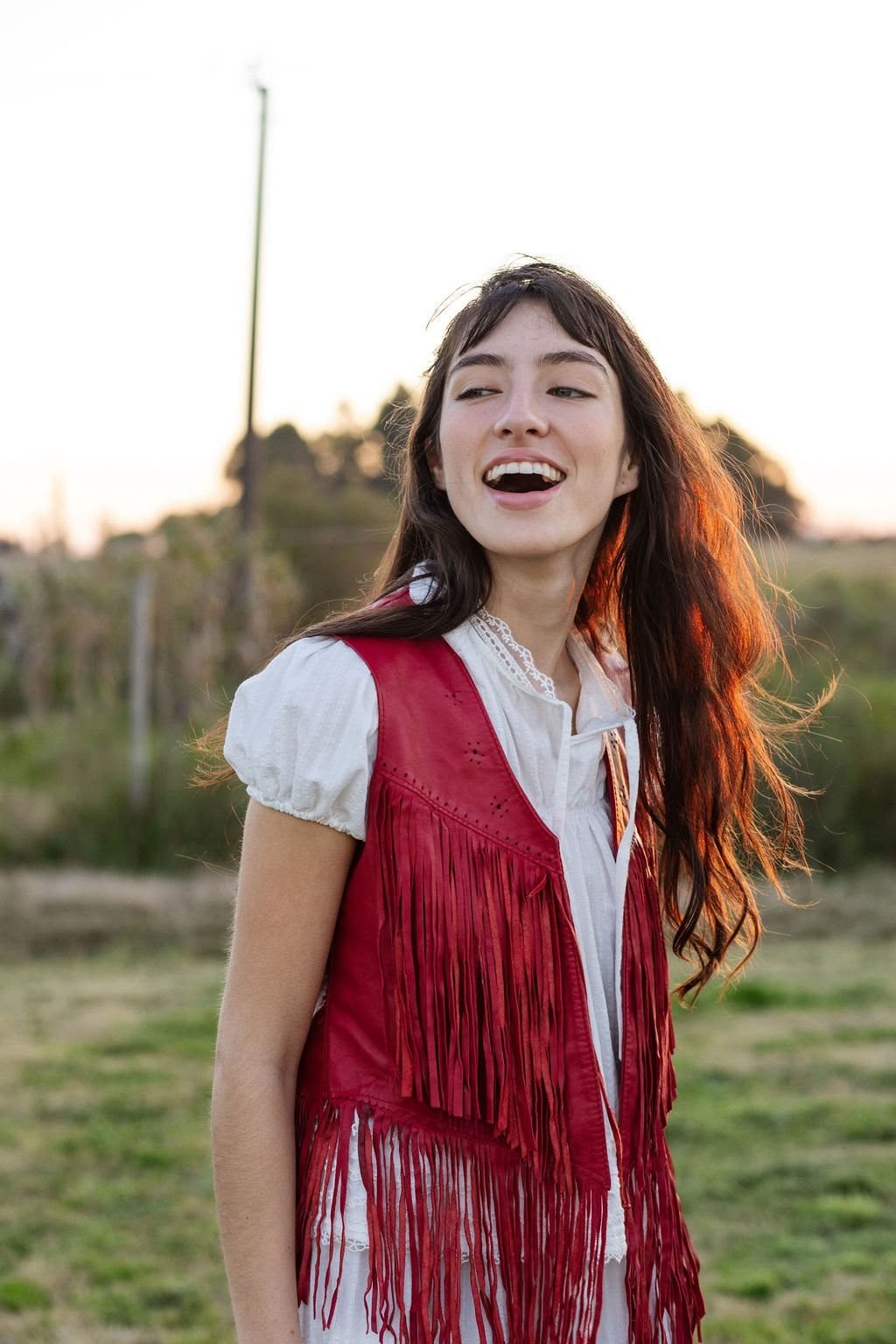 Chaleco rojo con flecos sobre blusa blanca